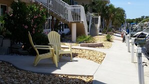 A beachfront property with a covered patio, a chair, and a staircase leading to a balcony.