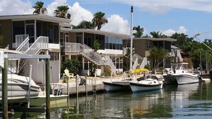 A marina with several boats docked, a building with a balcony, and a clear sky.
