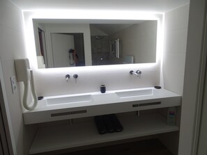Une salle de bain avec un lavabo blanc, un miroir et une douchette à main.