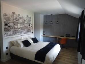 Un dormitorio con cama, un mural en la pared, un escritorio con silla y lámparas colgantes.