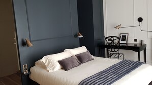 Un dormitorio con cama, lámparas de noche, escritorio y una silla.