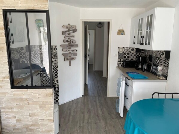 A compact kitchen with white cabinets, a blue table, and a patterned backsplash.