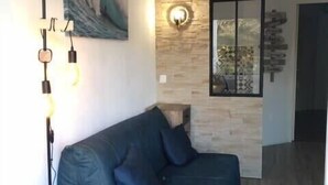 Un salon moderne avec un canapé bleu, une lampe sur pied, un luminaire fixé au mur et un tableau.