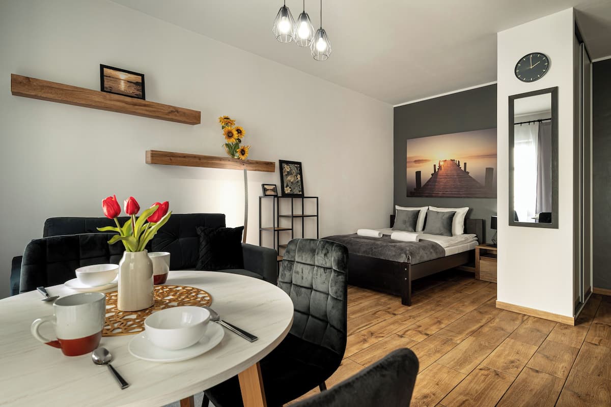 A modern room with a dining table, chairs, a sofa, a bed, and a painting on the wall.