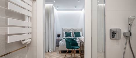A modern bathroom with a shower, a sink, and a bed with a headboard.
