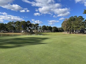 A golf course with a pond, trees, and houses in the background. - Family Friendly Villa 1202 with 27 Hole Golf Course Available and Great Resort Amenities by RedAwning (Calabash)