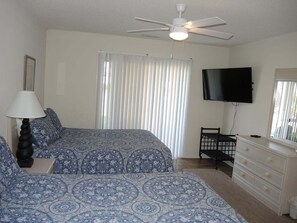 A bedroom with a bed, a dresser, a television, a ceiling fan, and a window with blinds. - 1202m 1 Bedroom Condo by RedAwning (Calabash)
