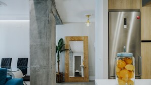 A modern kitchen with a stainless steel refrigerator, a glass jar of oranges on the counter, and a wooden-framed mirror. - Tribuna - Victoria 8 (Málaga)