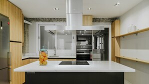 A modern kitchen with a central island, built-in oven, and stainless steel appliances. - Tribuna - Victoria 8 (Málaga)