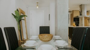 A dining area with a glass table, black upholstered chairs, and a large wooden bowl centerpiece. - Tribuna - Victoria 8 (Málaga)