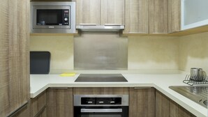 A modern kitchen with wooden cabinets, a built-in microwave, a stainless steel range hood, and a dishwasher. - Malagueta - Miradore II (Málaga)