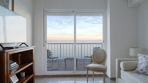 A room with a large window, a TV, a bookshelf, a chair, and a sofa. - Malagueta - Miradore II (Málaga)