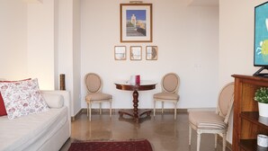A living room with a white sofa, two striped chairs, a small round table, and a framed picture above the table. - Malagueta - Miradore II (Málaga)