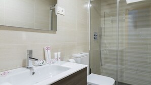 Ein modernes Badezimmer mit einem großen Waschbecken, einem Spiegel und einer Duschkabine aus Glas.