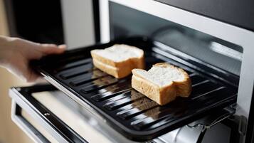 Uma mão colocando duas fatias de pão no forno.