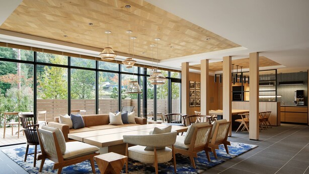 A spacious living area with a large wooden ceiling, a sofa set, and a dining table. - Fairfield by Marriott Tochigi Motegi (Motegi)