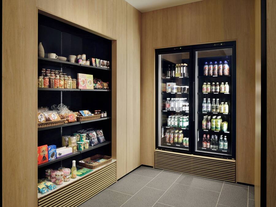 Un espace de rangement doté d’étagères remplies de divers produits alimentaires et d’un réfrigérateur contenant des boissons.