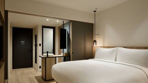 A modern hotel room with a large bed, a bedside table, a mirror, and a small desk with a lamp. - Fairfield by Marriott Tochigi Motegi (Motegi)