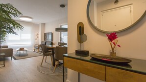 Una sala de estar moderna con comedor, un espejo grande y una planta en maceta.