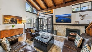 A spacious living room with leather sofas, a fireplace, and a stone fireplace surround.