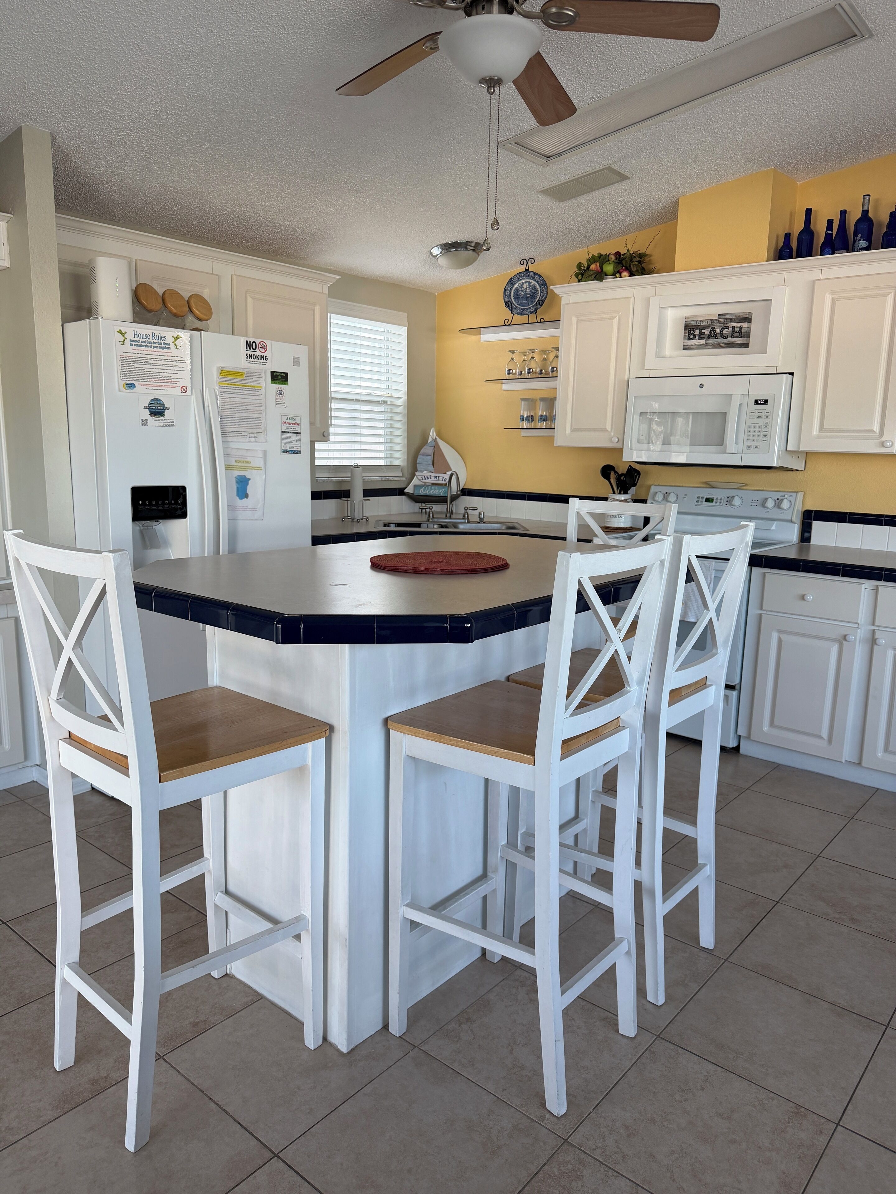 A kitchen with a central island, white cabinets, a microwave, and a ceiling fan.