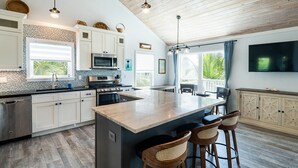 Una cocina moderna con una isla grande, electrodomésticos de acero inoxidable y una zona de comedor con taburetes de bar.