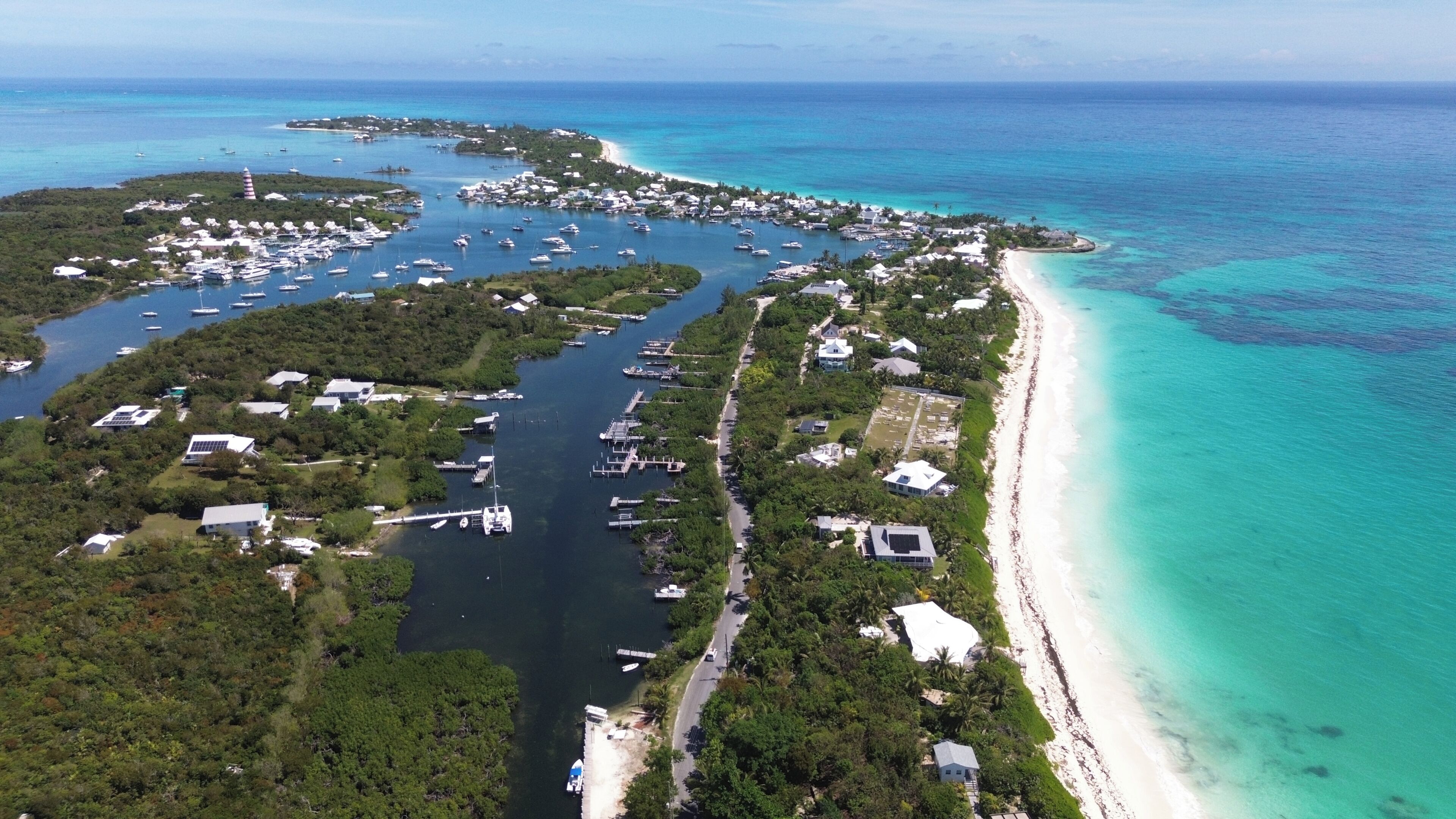 Luchtbeeld van een kustgebied met een jachthaven, boten en een strand.