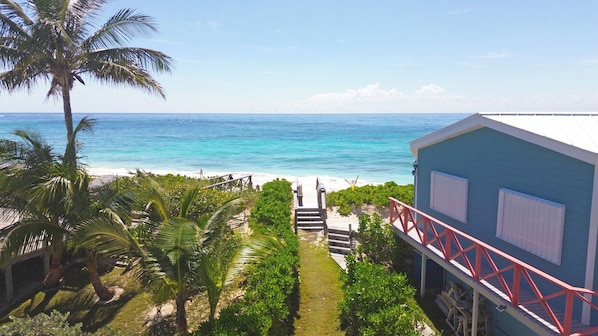 A coastal view with a staircase leading to a building with a red railing.