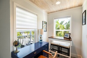 A room with a desk, chair, and two windows with blinds.