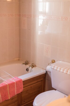 Bathroom features a white bathtub, toilet, and floral-patterned walls.