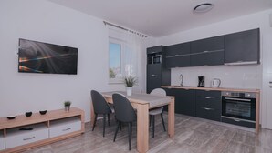 Moderni keittiö, jossa on ruokailutila. Tilaan kuuluu puinen pöytä, tuolit, televisio ja sisäänrakennetut kodinkoneet.