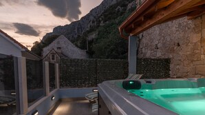Ein Whirlpool in moderner Außenanlage mit Steinmauer und Bergblick.