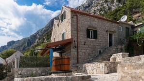 Ein Steinhaus mit rotem Ziegeldach, einer Holztür und einer Satellitenschüssel.
