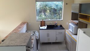 A compact kitchen with a window, a microwave, and a sink. - Cozy in Floripa (Florianópolis)