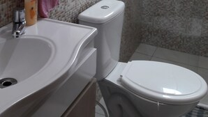 A bathroom with a white sink, a toilet, and a shower area. - Cozy in Floripa (Florianópolis)