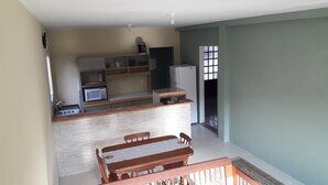 A compact kitchen with a microwave, a refrigerator, and a sink. There is a wooden dining table with chairs. - Cozy in Floripa (Florianópolis)