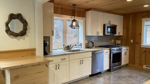 Une cuisine moderne dotée de meubles en bois, d’un lave-vaisselle en acier inoxydable, d’une cuisinière à gaz et d’un four à micro-ondes.