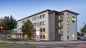 A modern B&B hotel with a flat facade, multiple balconies, and a well-lit entrance. - B&B Hotel Mannheim-Neuostheim (Mannheim)