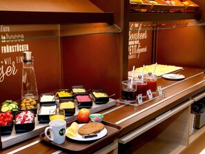 Buffet com diversas opções de comida, incluindo frutas, queijos e sucos.
