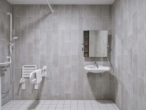 A modern bathroom with grey tiles, a white sink, a mirror, and a shower area. - B&B Hotel Mannheim-Neuostheim (Mannheim)