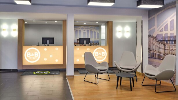 A hotel reception area with a modern design, featuring a reception desk, seating area, and a view of the lobby. - B&B Hotel Mannheim-Neuostheim (Mannheim)