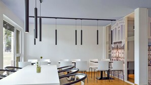 A modern conference room with a long table, white chairs, and pendant lighting. - B&B Hotel Mannheim-Neuostheim (Mannheim)
