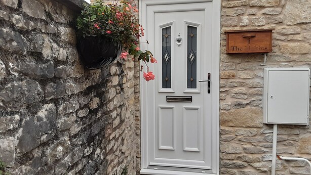 Une porte blanche avec une petite fenêtre, un mur de pierre et une enseigne au-dessus de la porte.