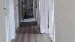 Un couloir étroit avec un plancher en bois et des murs blancs.