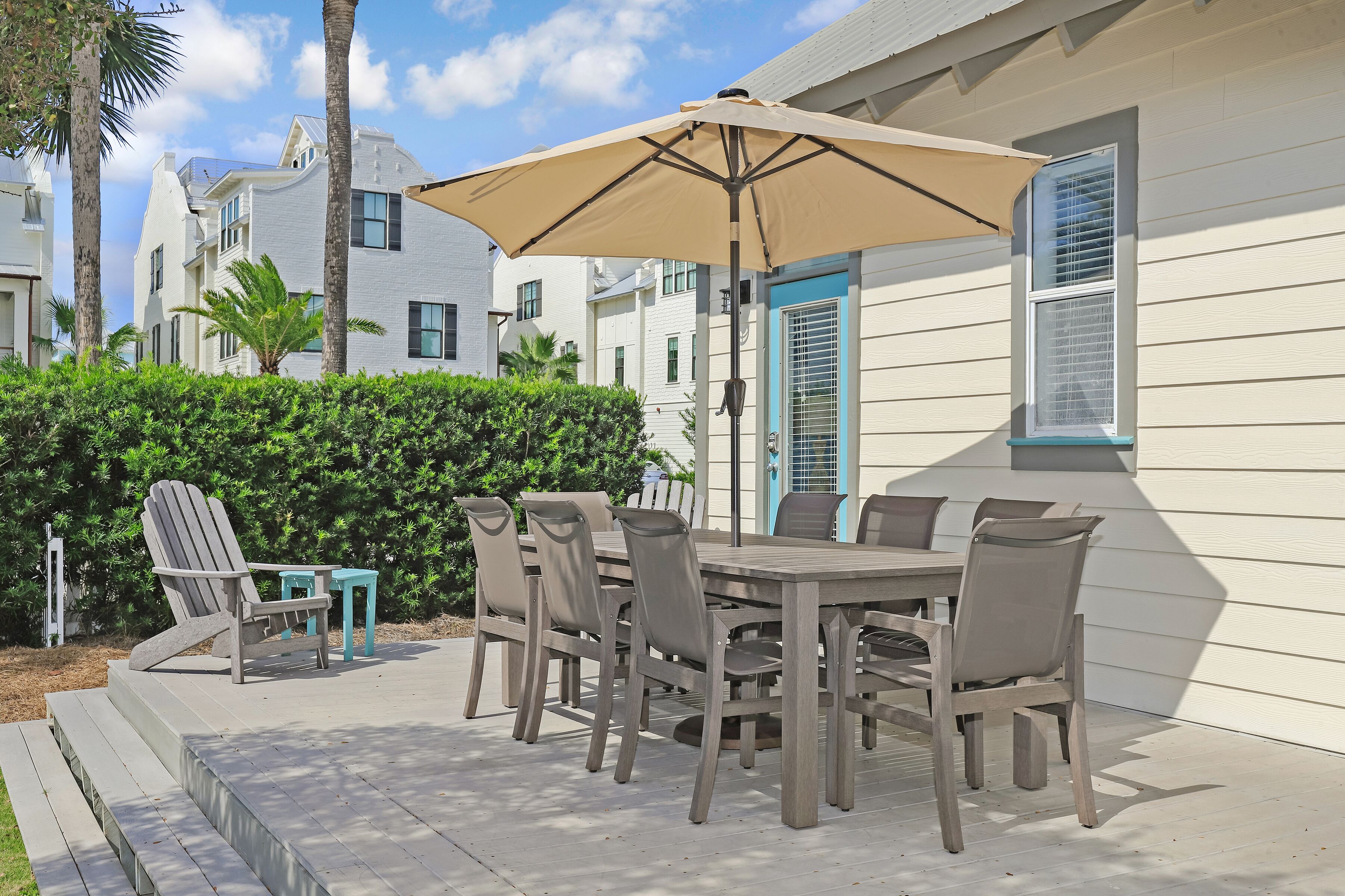 Une terrasse extérieure avec une table et des chaises, un parasol beige et une porte bleue.