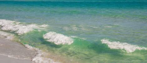 A beach with clear turquoise water and gentle waves.