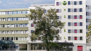 A modern hotel building with a prominent B&B logo, multiple floors, and a tree in front.
