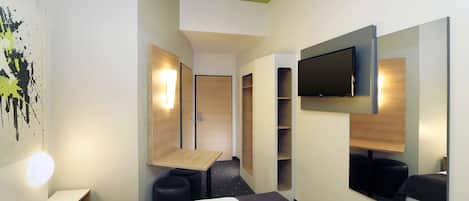 Una habitación de hotel moderna con cama, escritorio, televisor y armario.