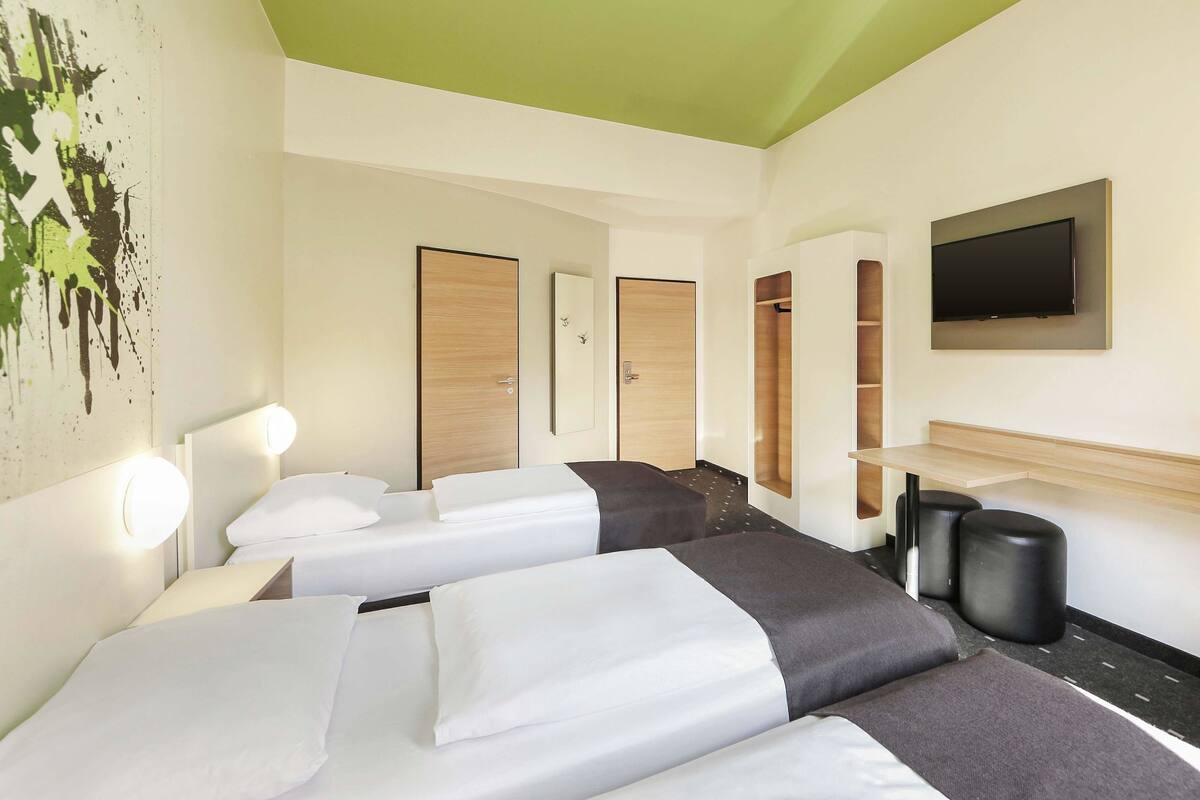 Une chambre d’hôtel avec deux lits, une télévision, un miroir et un plafond vert.