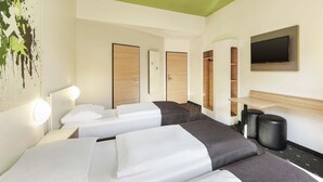 A hotel room with two beds, a TV, a mirror, and a green ceiling.